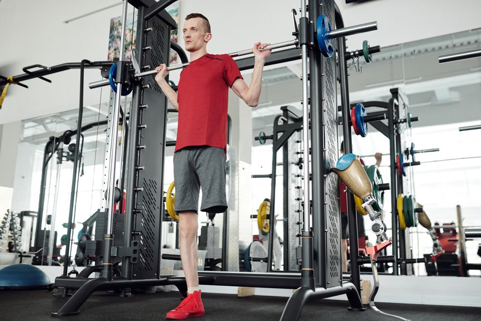 A determined amputee male lifting weights in a gym, showcasing strength and fortitude.