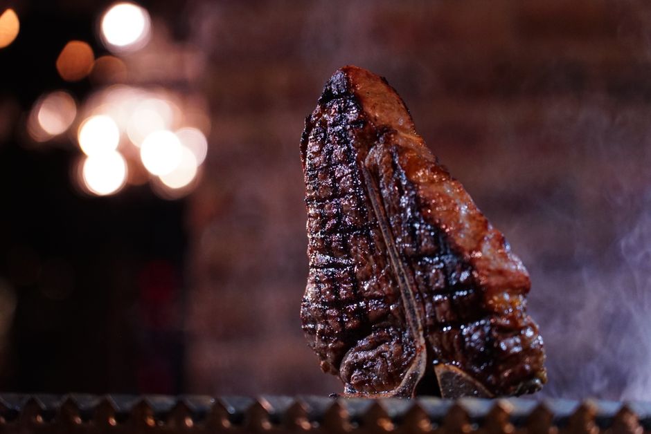Close-up of a perfectly grilled steak with a bokeh background, highlighting its juicy texture.