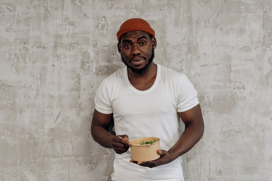 Smiling man in a white t-shirt enjoying a healthy meal indoors, embodying a fit lifestyle.